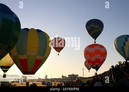 Die Menschenmassen in Osaki, Japan, beobachten bei Sonnenaufgang, wie Teams ihre Heißluftballons in den Morgenhimmel schießen. Stockfoto