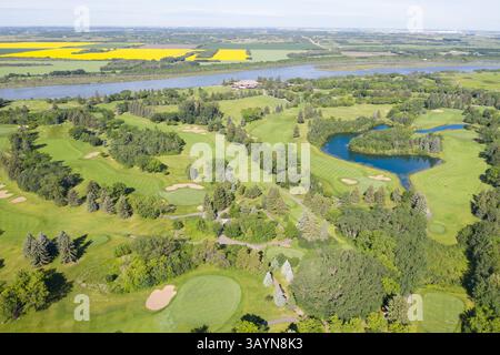 Golfplatz mit einem See im Hintergrund. Der Golfplatz ist von Bäumen umgeben und hat eine grüne Grasfläche Stockfoto