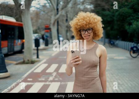 Junge Frau, die ihr Smartphone benutzt, während sie in der Stadt läuft Stockfoto