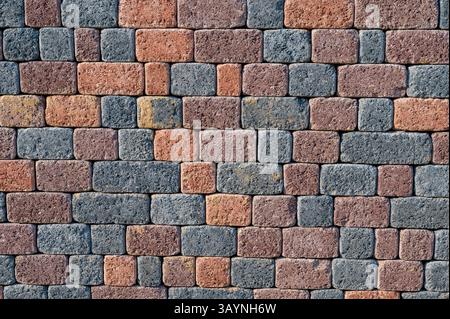 Nahaufnahme einer Wand oder eines Pflasters aus rechteckigen Steinpflastern oder Ziegeln in verschiedenen Grau-, Rot- und Brauntönen. Die raue Textur und wiederholen Stockfoto