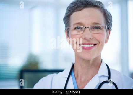 Ärztin lächelt in der Klinik in die Kamera, trägt Laborkittel, Brille und Stethoskop, Kopierraum Stockfoto