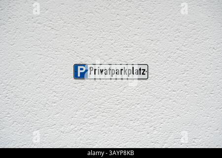 Ein Schild mit dem Aufdruck Privatparkplatz weist auf einen privaten Parkplatz auf, der an einer strukturierten weißen Wand befestigt ist. Nützlich zur Veranschaulichung von Parkbeschränkungen oder Stockfoto
