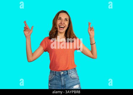 Die junge Frau drückt ihre Finger und wünscht sich viel Glück, in der Hoffnung, dass ihre Träume wahr werden Stockfoto