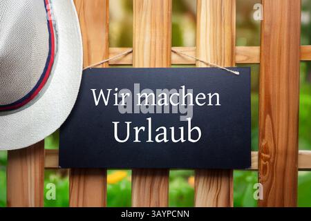Firmenfeiertage symbolisches Bild: Schild mit hinzugefügtem Text wir MACHEN URLAUB auf einem Holzzaun Stockfoto