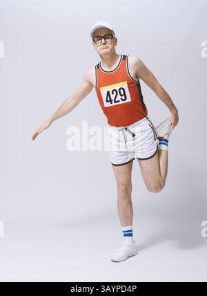 Der Athlet dehnt seine Beinmuskeln aus und macht sich auf das Rennen vorbereitet, ein durchgehendes Porträt, isoliert auf weißem Hintergrund Stockfoto