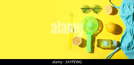 Komposition mit tragbarem Elektroventilator, frischen Zitronen und weiblichen Strandzubehör auf gelbem Hintergrund mit Platz für Text Stockfoto