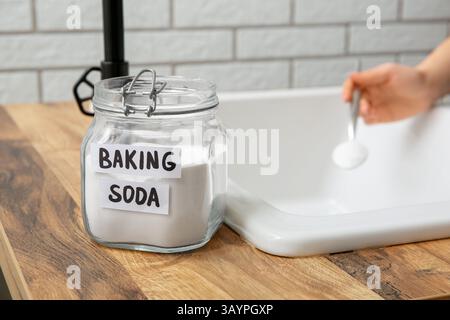 Frau, die verstopften Abfluss im Waschbecken reinigt, konzentrieren Sie sich auf ein Glas Backpulver Stockfoto