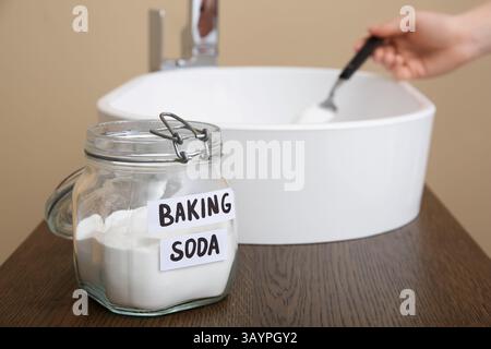 Frau, die verstopften Abfluss im Waschbecken reinigt, konzentrieren Sie sich auf ein Glas Backpulver Stockfoto