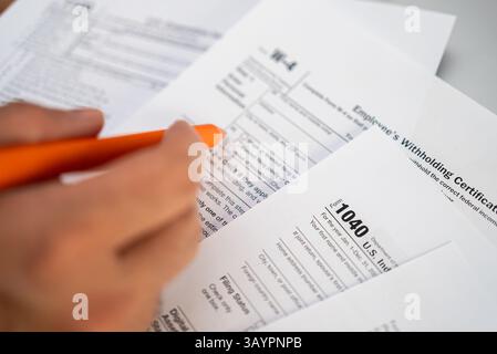 Männliche Freiberufler halten den Stift, der sich auf das Ausfüllen der notwendigen Steuerformulare für die Meldung des Jahreseinkommens vorbereitet Stockfoto