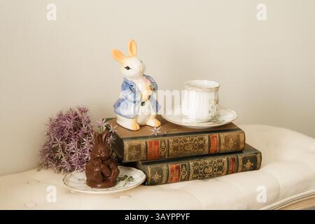 Alte Bücher, eine Tasse Kaffee und eine Kaninchenfigur auf dem Sofa Stockfoto