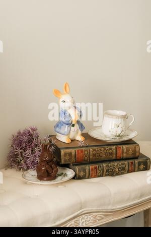 Alte Bücher, eine Tasse Kaffee und eine Kaninchenfigur auf dem Sofa Stockfoto