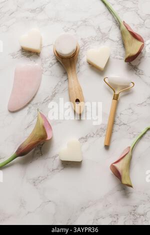 Flache Lay-Komposition mit Gua-Sha-Massagewerkzeugen auf weißem Marmorhintergrund Stockfoto