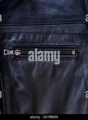 Eine Nahaufnahme einer Tasche und eines Reißverschlusses an einer schwarzen Lederjacke Stockfoto