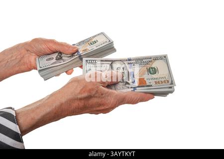Eine ältere Person hält und tauscht dicke Stapel von Hundert-Dollar-Scheinen Stockfoto