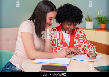 Zwei multiethnische junge Freundinnen, die zu Hause mit einem Laptop zusammen studieren Stockfoto