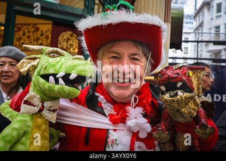 London, UK, 23. April 2025. Ein Zuschauer ist in voller St. George's Day-Outfit mit zwei Top-Drachen gekommen. Die Ewell St Mary's Morris Men treten in traditioneller Tracht mit Glocken und Taschentüchern auf, begleitet von Live-Musik. Bryn, das älteste Mitglied, ist 83. Anlässlich des St. George's Day findet auf dem Leadenhall Market traditionelle Morris-Tänze auf den Kopfsteinpflasterstraßen des viktorianischen Marktes statt. Stockfoto