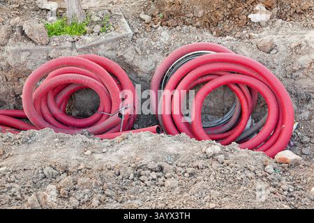 Verlegung der Kommunikation in den Boden mit roten Wellschläuchen. Stockfoto