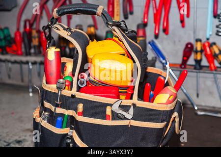 In der Werkstatt steht eine Elektrikertasche voller Werkzeuge. Stockfoto