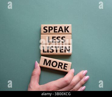Weniger sagen, mehr hören. Holzblöcke mit Wörtern sprechen weniger Hören Sie mehr. Wunderschöner graugrüner Hintergrund. Geschäftsmann Hand. Geschäftlich und sprich Stockfoto