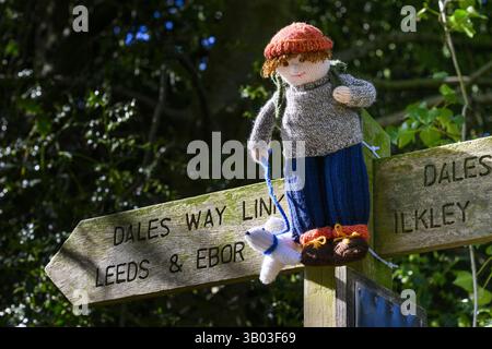 Yarnbombe Person am Fingerpfosten befestigt (öffentlicher Fernwanderweg, Ebor Way, Dales Way Link) Nahaufnahme - Menston, West Yorkshire, England Großbritannien. Stockfoto