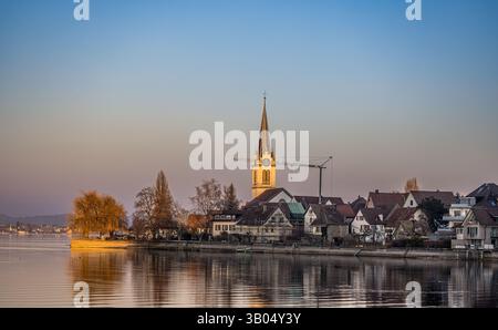 Berlingen, Schweiz, 8. Februar 2025: Blick über den Bodensee, wo die evangelische Kirche in Berlingen von der Abendsonne beleuchtet wird. (Foto von A Stockfoto