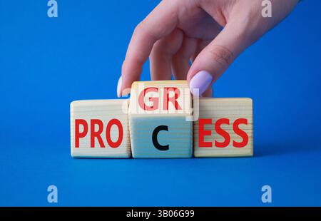 Symbol für Prozess und Fortschritt. Die Hand des Geschäftsmannes dreht Holzwürfel und ändert das Wort Prozess und Fortschritt. Wunderschöner blauer Hintergrund. Business und PR Stockfoto