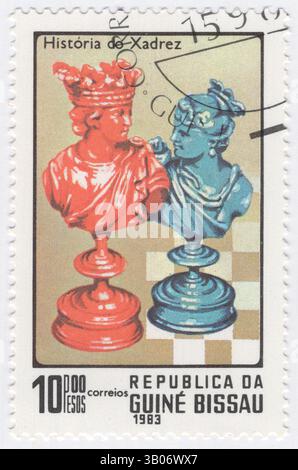 GUINEA-BISSAU - 13. Juni 1983: 10 Peso Briefmarke mit den Schachfiguren König und Königin. Geschichte des Schachs. Schach ist ein abstraktes Strategiespielspiel für zwei Spieler, das keine versteckten Informationen und keine Zufallselemente beinhaltet. Es wird auf einem quadratischen Spielbrett gespielt, einem sogenannten Schachbrett mit 64 Quadraten, die in einem 8 x 8 Raster angeordnet sind. Die Spieler, die als „weiß“ und „Schwarz“ bezeichnet werden, kontrollieren jeweils 16 Stücke: Einen König, eine Königin, zwei Bäche, zwei Bischöfe, zwei Ritter, und acht Schachfiguren; jede Art von Stück hat ein anderes Bewegungsmuster Stockfoto