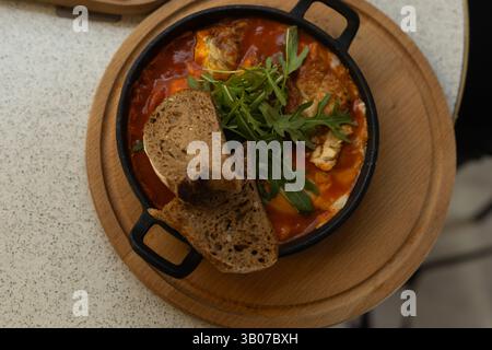 Shakshuka in einer Pfanne mit Brotscheiben, Blick von oben, Frühstück Stockfoto
