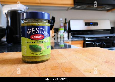 Ein Glas mit cremiger Genovese-Pesto-Sauce von Barilla auf einem Schneidebrett in einer Küche; ein Produkt aus Italien, das von Barilla America in den USA verkauft wird. Stockfoto
