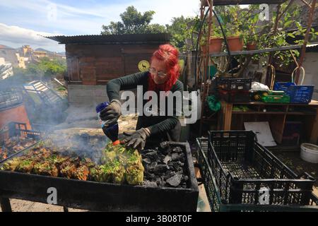 Frauen bei der Verarbeitung von gerösteten Artischocken typisches Gericht der kulinarischen Tradition Süditaliens in der Osterzeit. Stockfoto