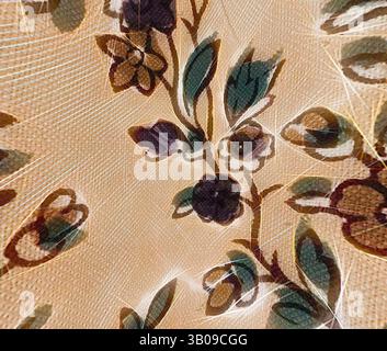 Eine Nahaufnahme eines strukturierten Stoffes mit einem zarten Blumenmuster, mit komplexen Blättern und Blüten in satten Farben, die ein elegantes und künstlerisches Aussehen schaffen. Eine runde Platte mit einem zarten Blumenmuster mit leuchtenden Blumen und komplexen Blättern vor einem warmen, neutralen Hintergrund. Klassische Kunst mit einem modernen Twist von Artotop, transformierte französische Stoffe, erste Hälfte des 19. Jahrhunderts, klassische Kunst mit einem modernen Twist von Artotop Stockfoto