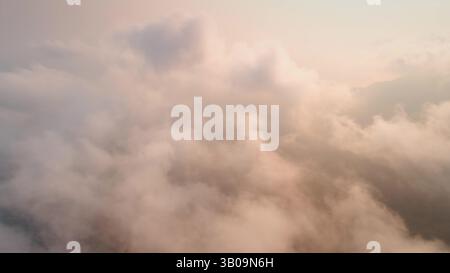 Genießen Sie einen atemberaubenden Blick aus der Luft auf flauschige Wolken während Sonnenuntergang und schaffen Sie eine ruhige Atmosphäre voller warmer Pastellfarben, die Ruhe und Schönheit hervorrufen Stockfoto