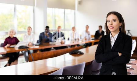 Porträt einer ehrgeizigen jungen Geschäftsfrau im Konferenzraum vor dem Hintergrund eines Teams ihrer Kollegen Stockfoto