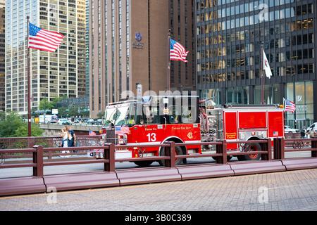 Chicago, Illinois, Vereinigte Staaten von Amerika - 22. August 2024: Feuerwehrauto der Chicago Fire Department Engine 13 auf der DuSable Bridge, amerikanische Fahnen wehen Stockfoto