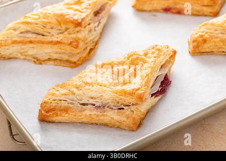 Blätterteiggebäck mit Kirsch- oder Beerenmarmelade auf einem frisch gebackenen und verzehrfertigen Backblech Stockfoto