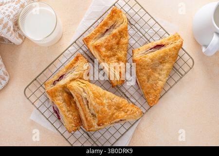 Blätterteiggebäck mit Kirsch- oder Beerenmarmelade auf einem frisch gebackenen und verzehrfertigen Backblech Stockfoto