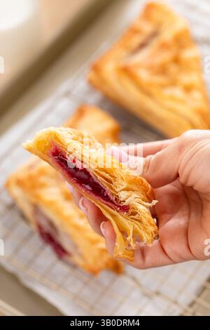 Das Gebäck mit Kirsch- oder Beerenmarmelade auf einem frisch gebackenen Backblech in zwei Hälften verteilen, um die Füllung zu zeigen Stockfoto