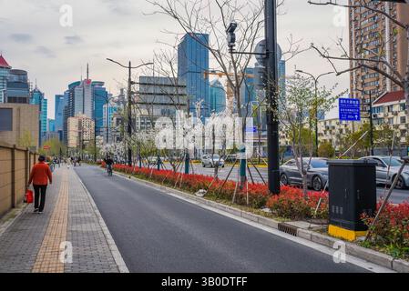 Shanghai, China - 1. April 2025: Pudong Skyline in der Abenddämmerung mit blühenden Bäumen. Einheimische laufen in der Nähe des Finanzviertels. Frühlingssaison. Stockfoto