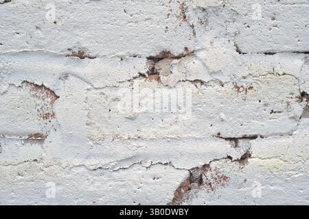Eine strukturierte, verwitterte weiße Ziegelwand mit abblätternder Farbe und einzigartigen Strukturmustern Stockfoto