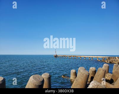 Tidal Gauge Pier und Betontetrapoden am Coastal Horizon Stockfoto
