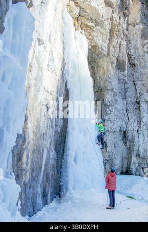 Canmore, Alberta, Kanada - 22. Januar 2022: Ein Mann und eine Frau klettern an einem warmen Wintertag auf einem Wasserfall, der zum Training im Grotto Canyon genutzt wird. Stockfoto