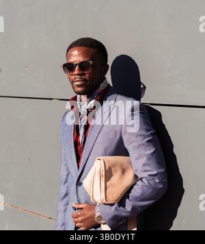 Stilvoller Geschäftsmann mit Sonnenbrille und eleganter Tasche, die an einer Wand befestigt ist Stockfoto