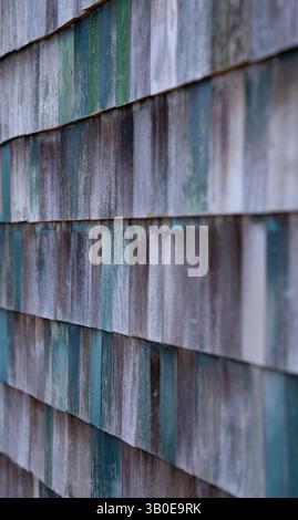 Holz schüttelt Schindeln an der Seite des alten Gebäudes gemalte Grüntöne und verblasste vertikale Bilder, die von Schichten einzelner Holzquadrate aufgenommen wurden Stockfoto