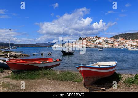 Traditionelle Fischerboote am Ufer mit Blick auf die charmante Stadt Poros, Griechenland, mit ruhigem Meer und blauem Himmel. Authentischer Blick auf die Mittelmeerküste. Stockfoto