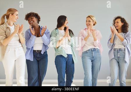 Fünf verschiedene Frauen in modischer Kleidung, treffen sich, lächeln, klatschen in die Hände Stockfoto