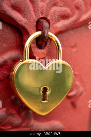 Nahaufnahme des herzförmigen Schlosses mit rotem Metallhintergrund vertikales Bild mit Raum für Typ, der Liebe Ehe Verbindung darstellt gute Valentinskarte Stockfoto