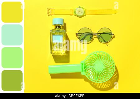 Tragbarer elektrischer Ventilator und stilvolles weibliches Zubehör auf gelbem Hintergrund. Verschiedene Farbmuster Stockfoto