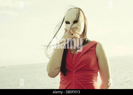 Porträt einer eleganten Frau mit weißer Maske vor dem Gesicht, Konzept von Identität und Geheimnis Stockfoto