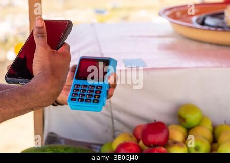 Nahaufnahme der modernen NFC-Zahlungsmethode mit Händen, die ein POS-Terminal und ein Mobiltelefon halten Stockfoto