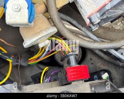 Nahaufnahme eines Kabelsteckverbinders für einen Fahrzeugmotor mit roter Sicherungslasche und mehrfarbigen Kabeln, Teil des elektrischen Kabelbaums des Fahrzeugs, der sich im Motor befindet Stockfoto